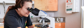 Student in science lab using microscope