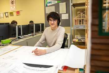 Student revising paper draft of building.