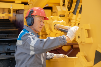 Mechanic checks hydraulic hose system equipment on excavator to raise bucket 