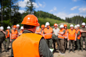 Person in safety gear talking to group of people in safety gear