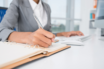 Woman writing in notepad at a desk