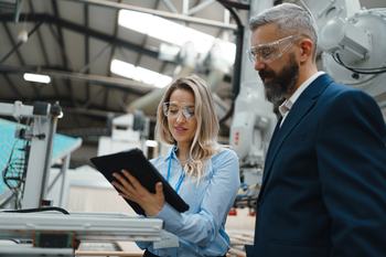 Female manager in manufacturing plant reviewing tablet.