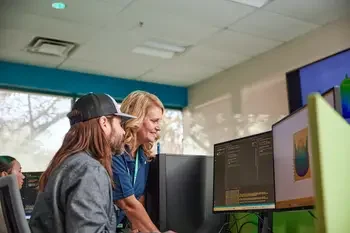 CWI teacher assisting student on computer.