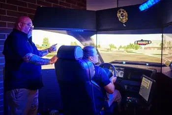 Law enforcement instructor teaching student in simulator.