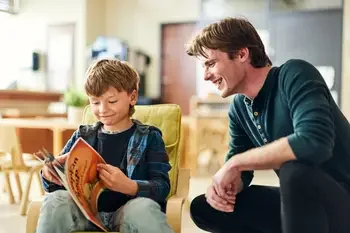 Teacher helping student read a book.