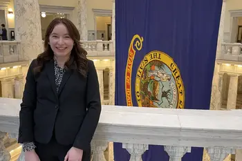 Student standing by state flag in the capital building