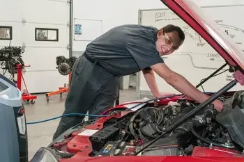Student working on electrical equipment on car