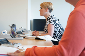 Students sitting at table with paperwork and calculators