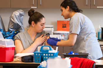 Medial Assistant students in lab practicing giving shots to patient