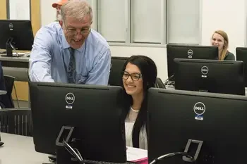 Instructor helping student at computer in classroom