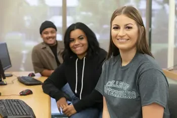 CWI students in a computer classroom sitting in a row looking at the camera