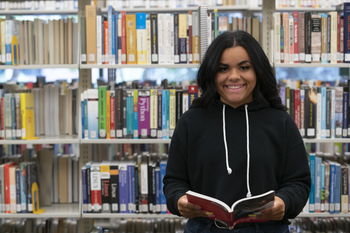 CWI student holding a book in the library