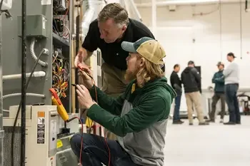 CWI student and instructor at a piece of equipment with a meter