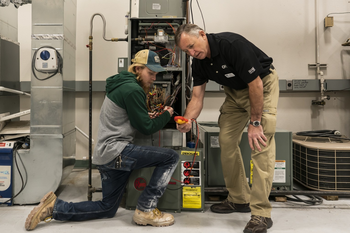 HVAC instructor and student working on furnace