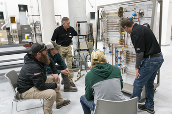 Instructor showing group of students components on an HVAC system