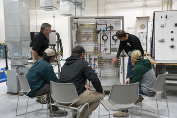 Instructor showing group of students components on an HVAC system