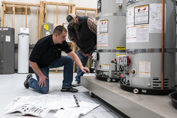Plumbing instructor and student examining a water heater