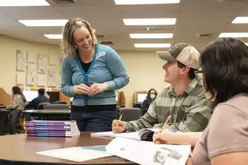Instructor helping two students at a table in a classroom