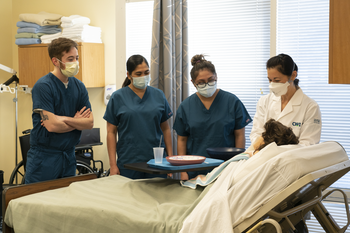 Hemodialysis Technician students in healthcare lab standing around patient's bed