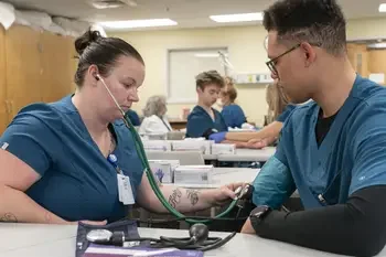Two CWI students in a medical classroom using blood pressure equipment