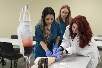 Instructor showing students how to take blood in a healthcare lab