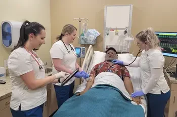 Group of CWI students in scrubs over a mannequin
