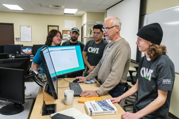 CWI students and instructor gathered around a computer