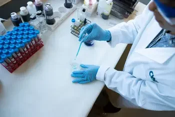 Looking down on a CWI student in a lab adding liquid to a beaker