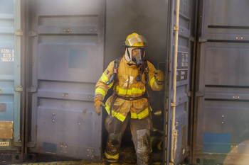 Fire fighter coming out of smoke filled container