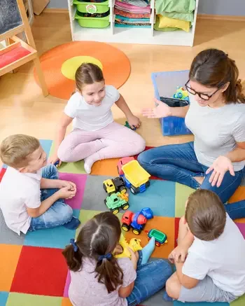 Person sitting in classroom in circle with group of kids