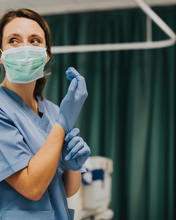 Nurse in a hospital setting putting on a glove