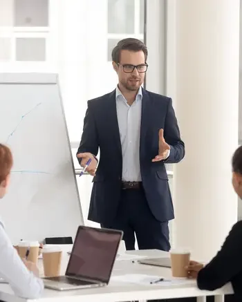 Man standing and giving a presentation in front of a group of people in a meeting