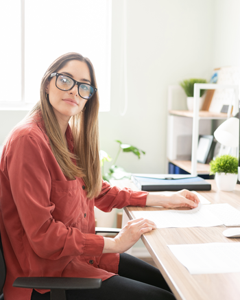 Person with glasses sitting at a desk with a computer