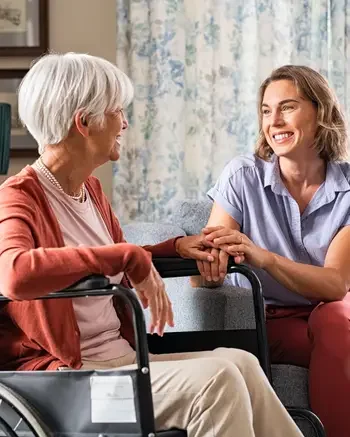 A young women smiling with an older woman in a wheel chair