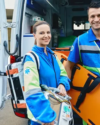 Two people in emergency uniforms standing in front of ambulance