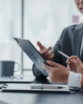 Two people at a desk looking at a tablet