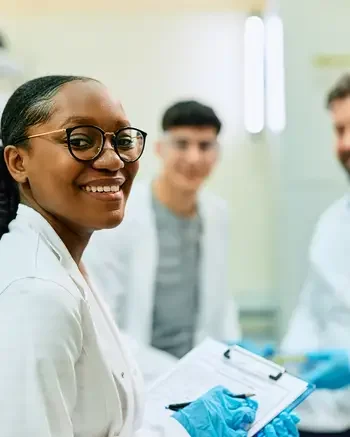 A grooup of people in lab coats and one is looking at the camera