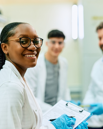 A grooup of people in lab coats and one is looking at the camera