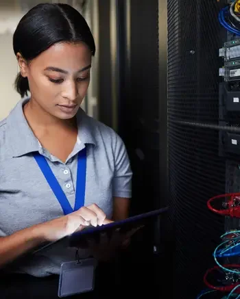 Woman looking at tablet next to server equipment