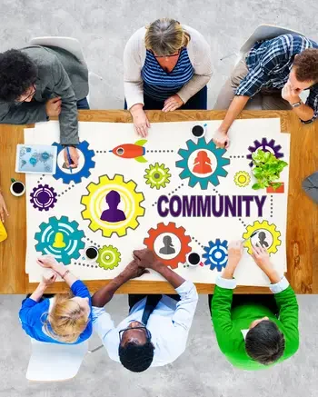 People sitting around a rectangle table painting a banner