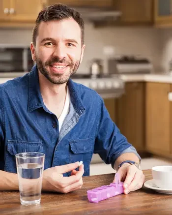 Male sitting at a table with a daily pill tracker