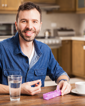 Male sitting at a table with a daily pill tracker