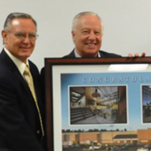 Close up of two men in suits holding a large picture frame of CWI campus.