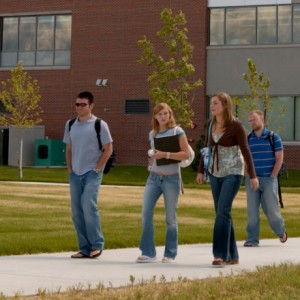 Four students walking along sidewalk.
