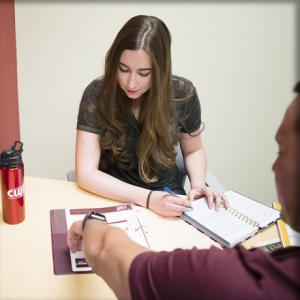  Female student sitting at a table getting help from an advisor