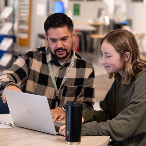 Advisor assisting student on a laptop