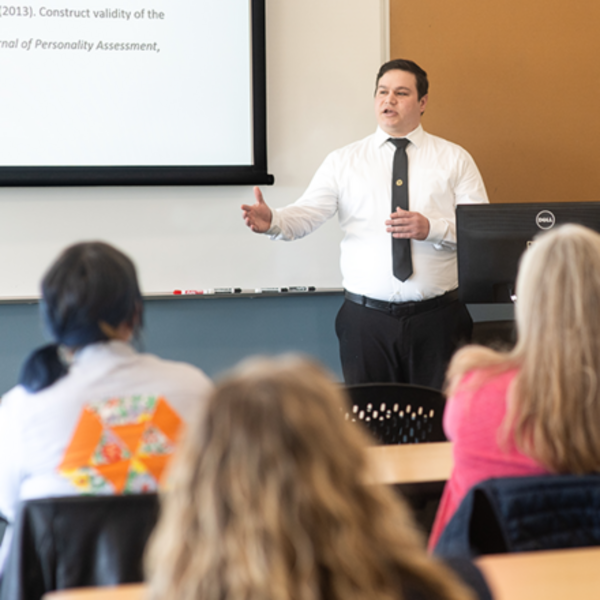 student speaking at the front of a classroom to students