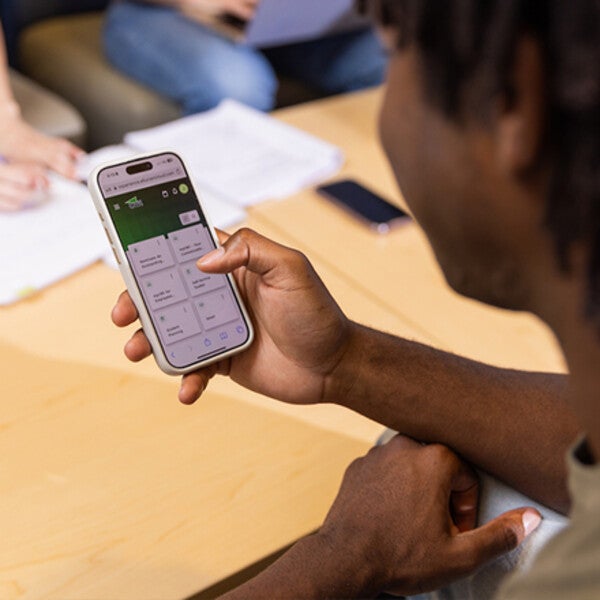 Student holding a cell phone and scrolling through content.