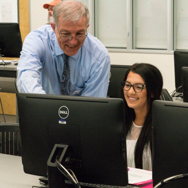 Instructor helping student at a computer station