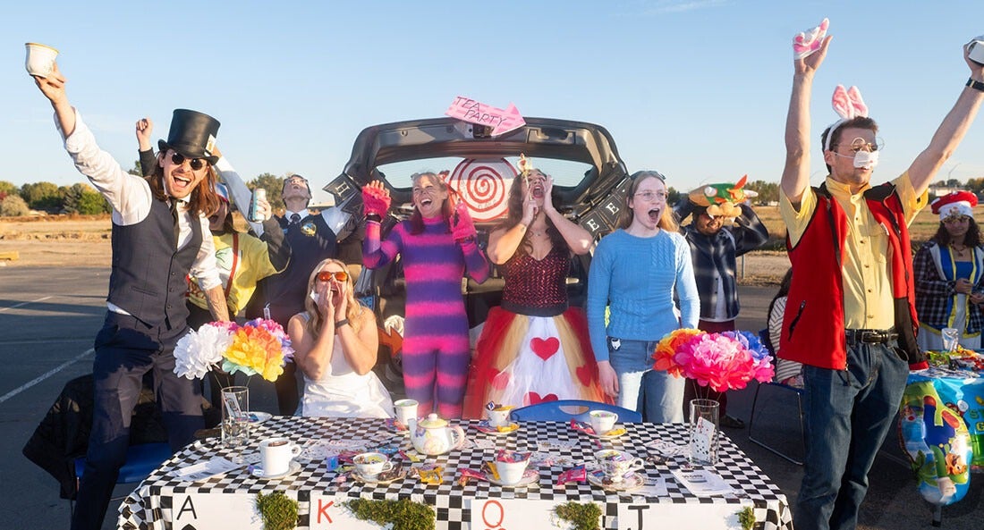 Students celebrate in front of their Halloween Trunk or Treat booth dressed as characters from Alice in Wonderland.